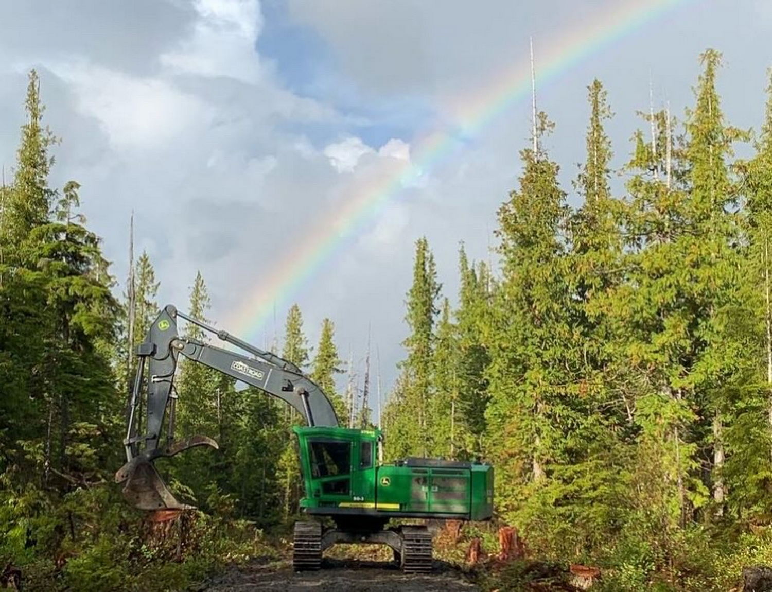 Excavator under a rainbow in forest